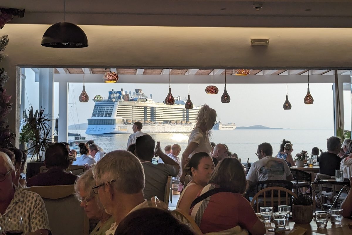 View from a waterfront restaurant in Mykonos as a cruise ship departs