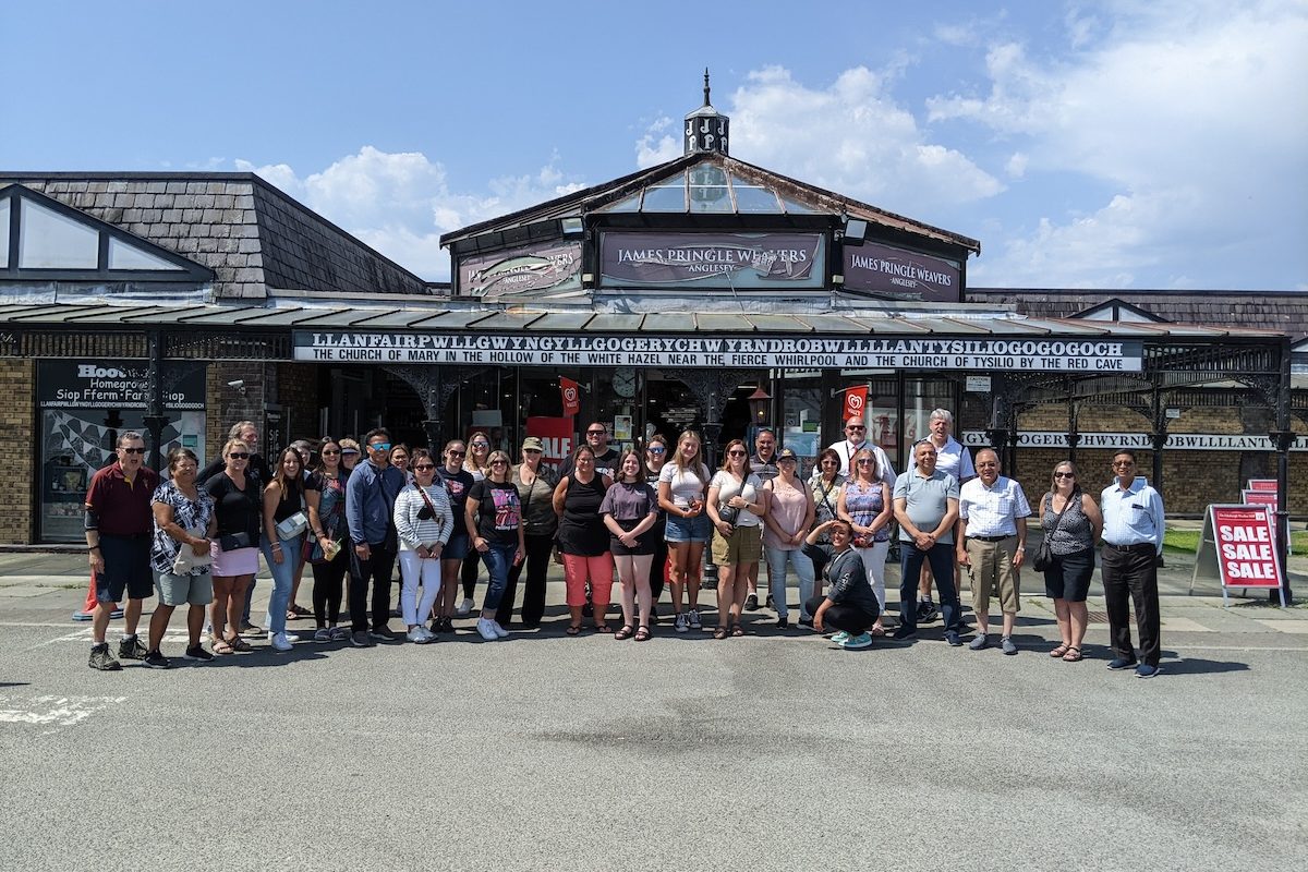 Best of UK & Ireland tour review - Expat Explore group photo in front of Llanfairpwllgwyngyllgogerychwyrndrobwllllantysiliogogogoch